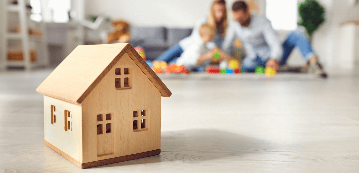 family playing in the background behind a toy house