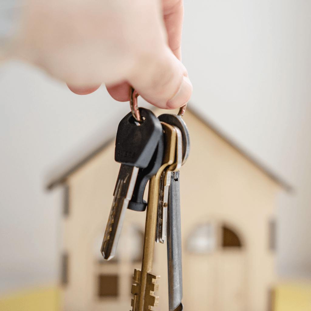 set of keys being held in front of a house